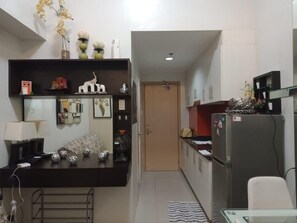 A compact kitchen with a refrigerator, a microwave, and a small dining area with a table and chairs. - Jericho's Place at Sea Residences (Pasay)