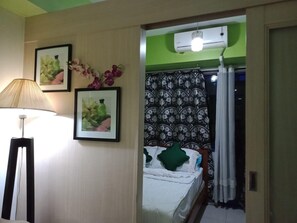 A bedroom with a bed, a lamp, and two framed pictures on the wall. - Jericho's Place at Sea Residences (Pasay)