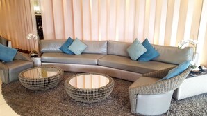 A modern living room with a curved sofa, two round wicker coffee tables, and a fluffy rug. - Jericho's Place at Sea Residences (Pasay)