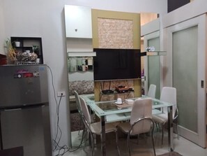 A compact kitchen with a refrigerator, a glass dining table, and chairs. - Jericho's Place at Sea Residences (Pasay)