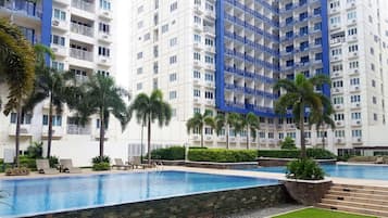 A hotel with multiple floors, a swimming pool, and palm trees.