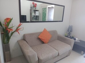 A living room with a sofa, a mirror, a vase with flowers, and a small table with candles. - Jericho's Place at Sea Residences (Pasay)