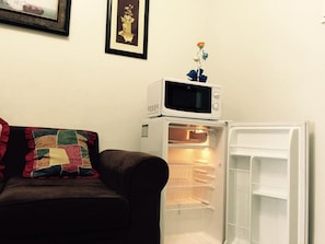 A living room with a couch, a microwave, and an open refrigerator. - Jericho's Place at Sea Residences (Pasay)