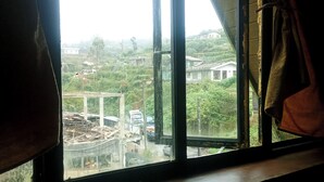 A window with a view of a construction site and surrounding buildings. - The heaven wood cabin (Nuwaraeliya)