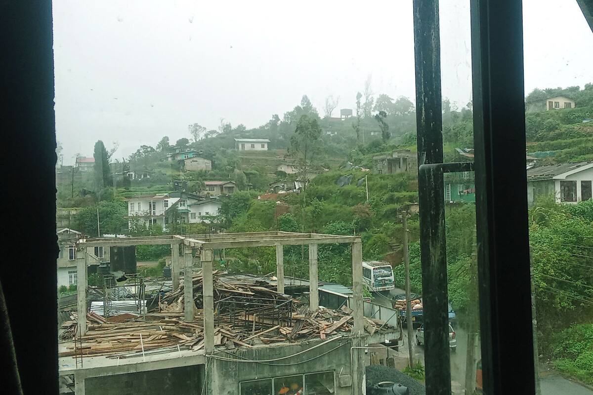 A view through a window of a construction site with a partially built structure and surrounding residential houses.