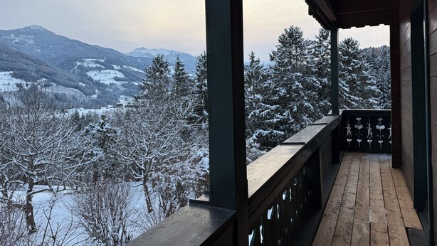 A wooden balcony with a view of snow-covered mountains and trees. - Large mountain house in Mitterberg near Hauser Kaibling (Mitterberg)
