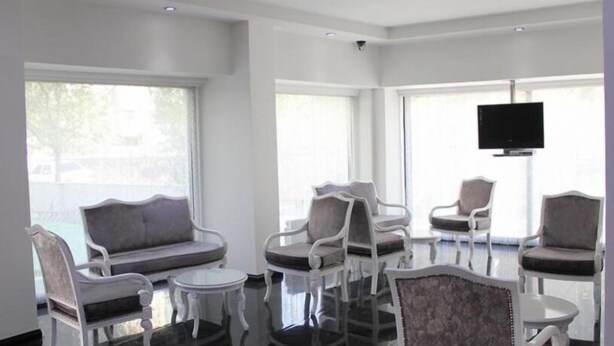Eine moderne Lounge mit einer Couch, Sesseln und einem Fernseher.