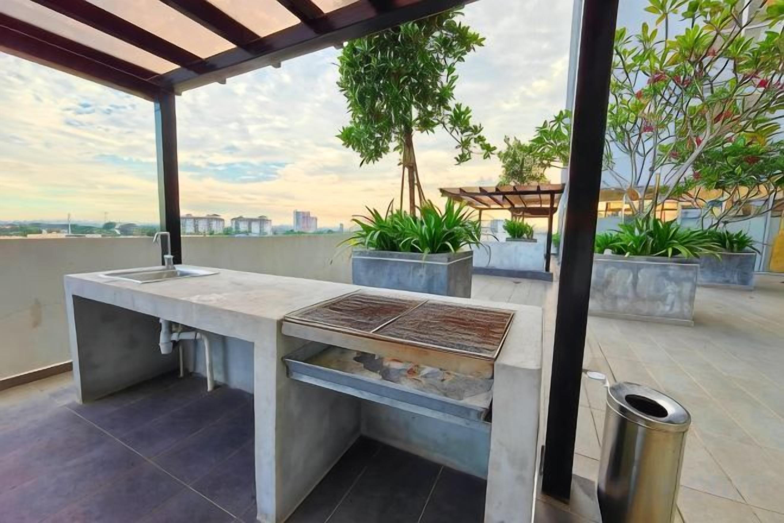 Un área de cocina al aire libre con pileta, parrilla y plantas en macetas.