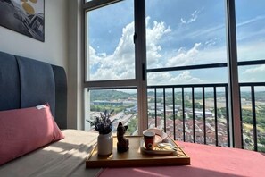A room with a bed, a window with a view of a cityscape, a balcony, and a tray with items on the windowsill. - ABHome [Friday Suite] Midas Seri Alam #Masai #JB (Plentong)