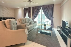 Un salon moderne avec un canapé, une table basse, un téléviseur et un balcon agrémenté de rideaux.