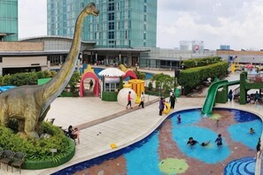 A dinosaur statue, a water play area, and a building with a modern design. - ABHome [Family Suite] KSL D'Esplanade #Pool View #JB (Johor Bahru)