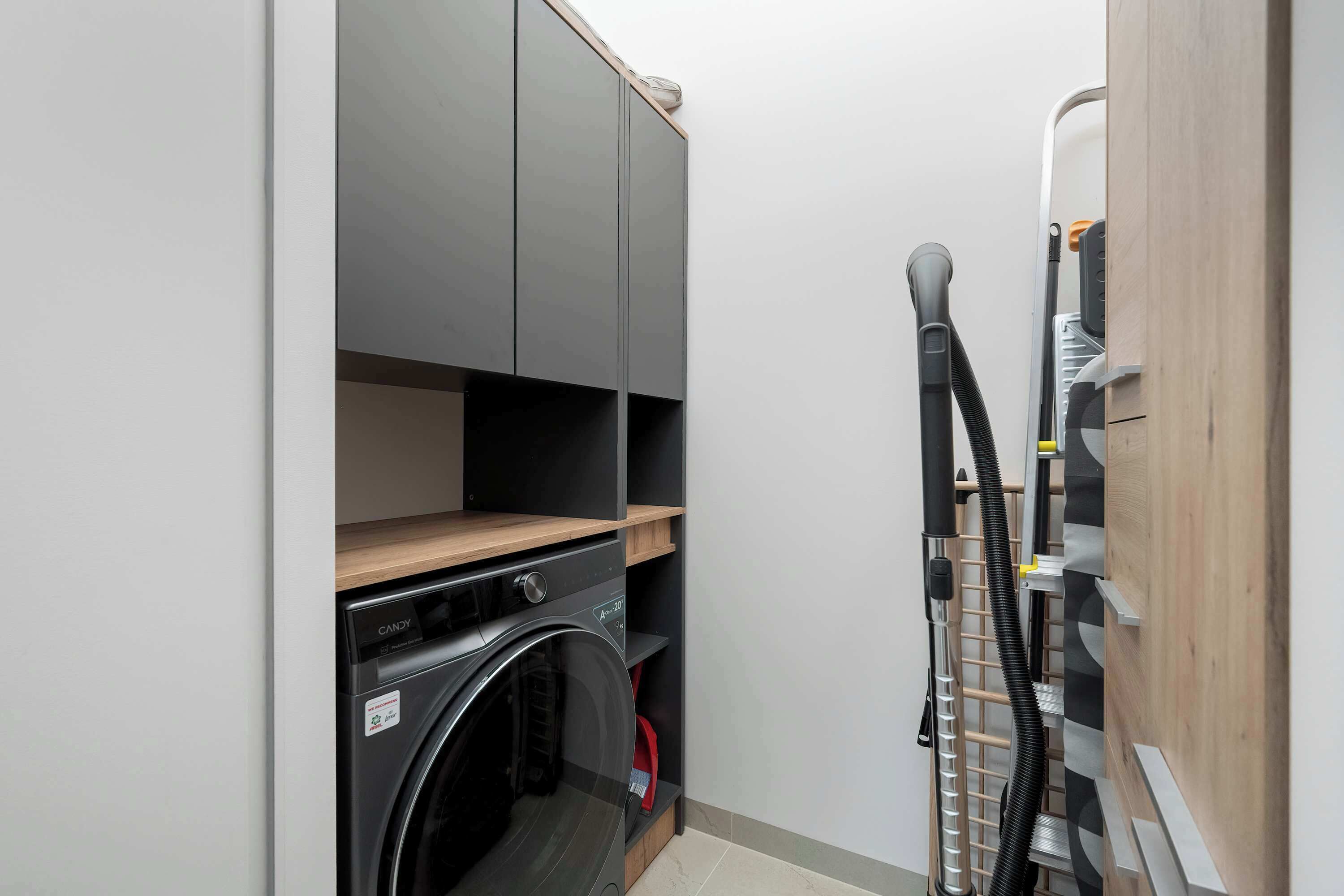 Une petite buanderie équipée d’un lave-linge, d’un sèche-linge et d’un aspirateur.