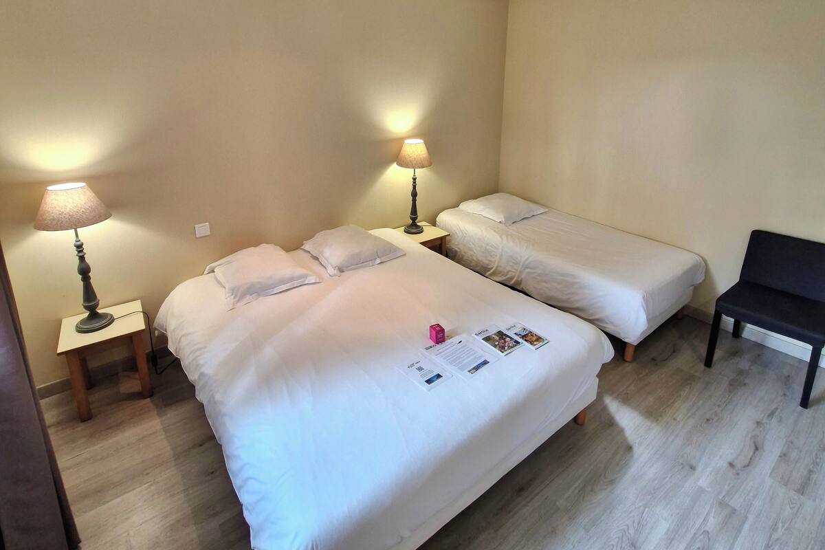 Ein Hotelzimmer mit zwei Betten, einem Schreibtisch, einem Stuhl und einer Lampe.