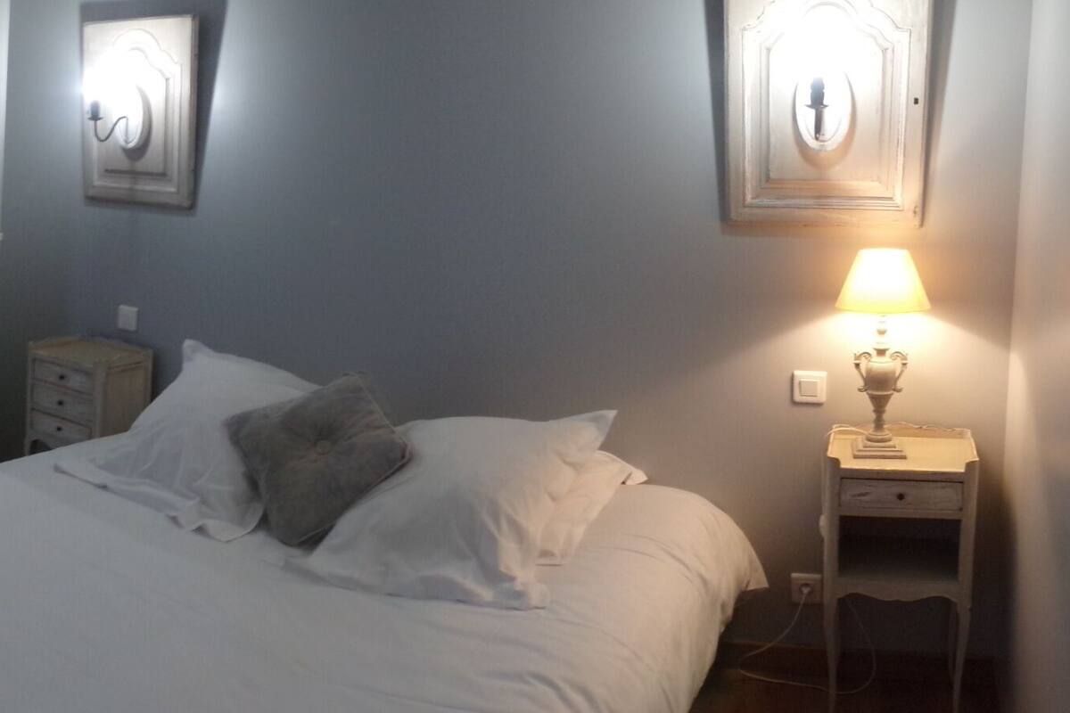 Ein Schlafzimmer mit einem Bett, einem Nachttisch mit Lampe und einer Tür zu einem Badezimmer.