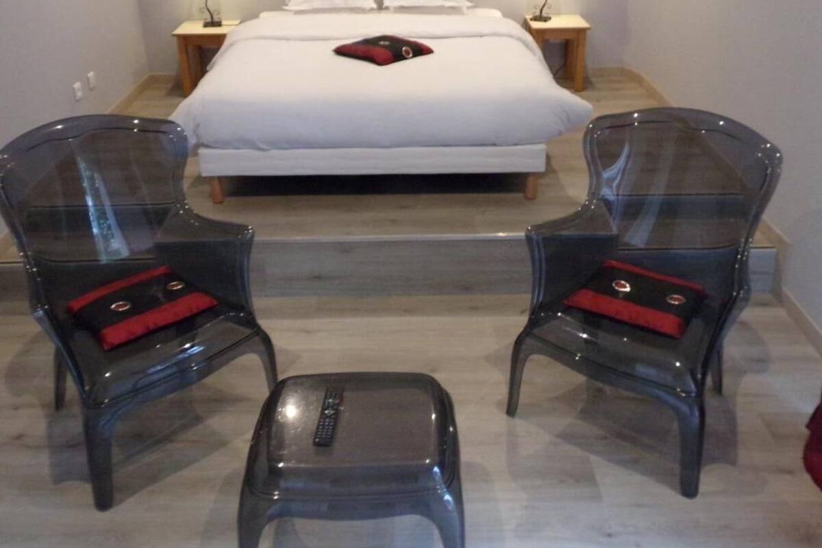 Ein Schlafzimmer mit einem Bett, zwei Nachttischen, zwei Stühlen und einem kleinen Hocker.