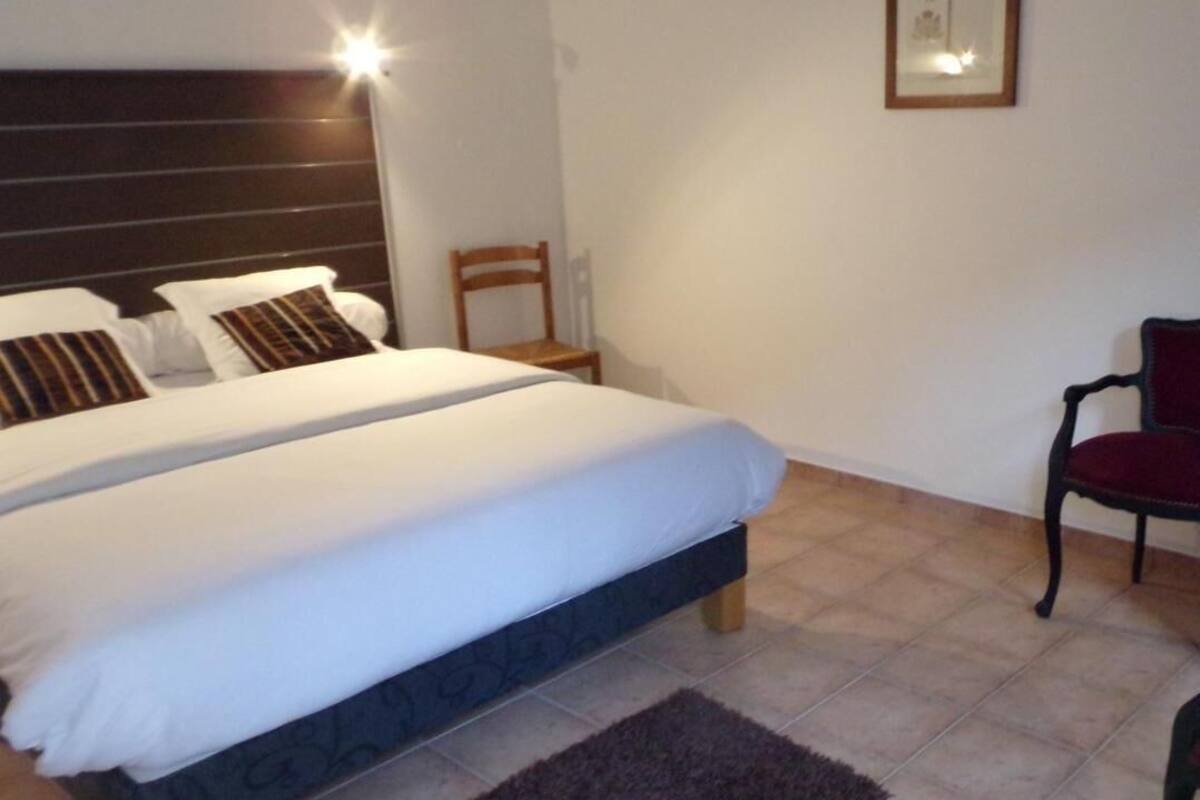 Ein Schlafzimmer mit einem Doppelbett, einem Nachttisch, einem Sessel, einer Lampe und einem gerahmten Bild an der Wand.