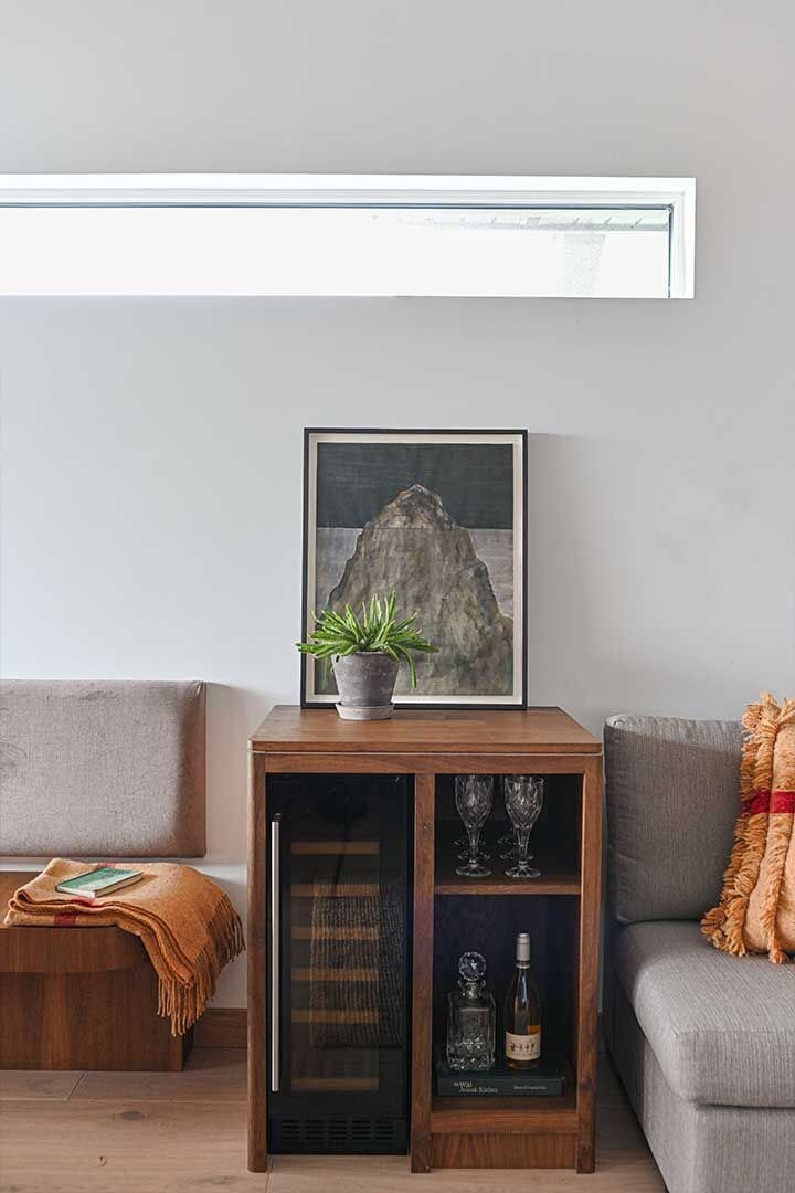 A modern living room with a wooden sideboard, a framed artwork, a potted plant, and a grey sofa.