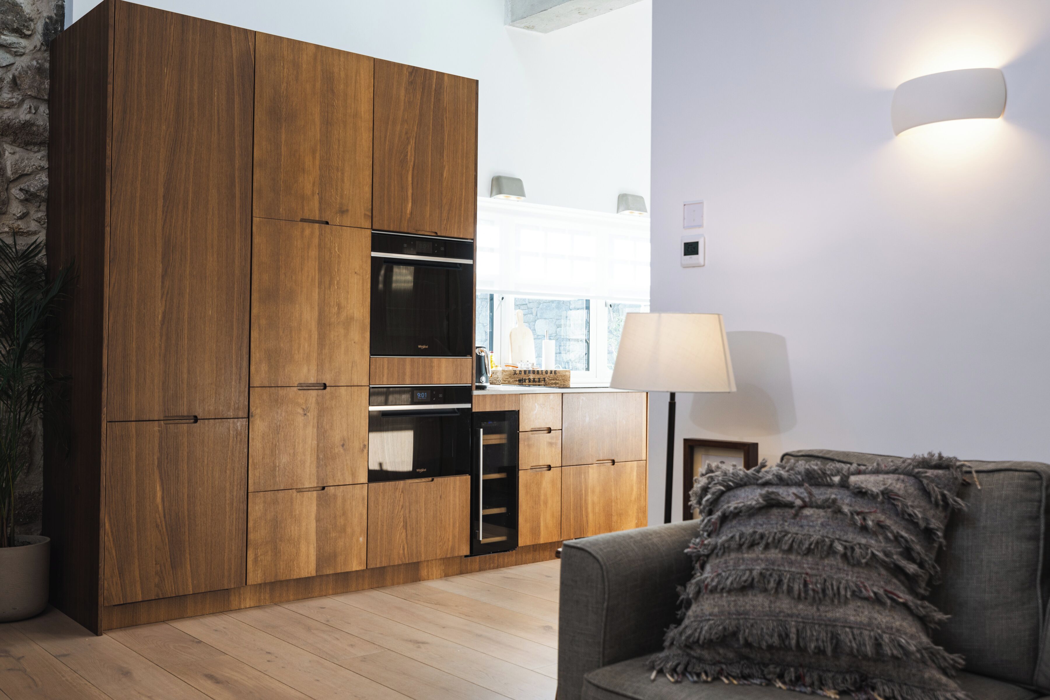 Una cocina moderna con armarios de madera, horno empotrado y ventana con vistas.