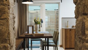 A dining area with a stone archway, wooden furniture, and a vase with flowers. - Within the Village (Roundstone)