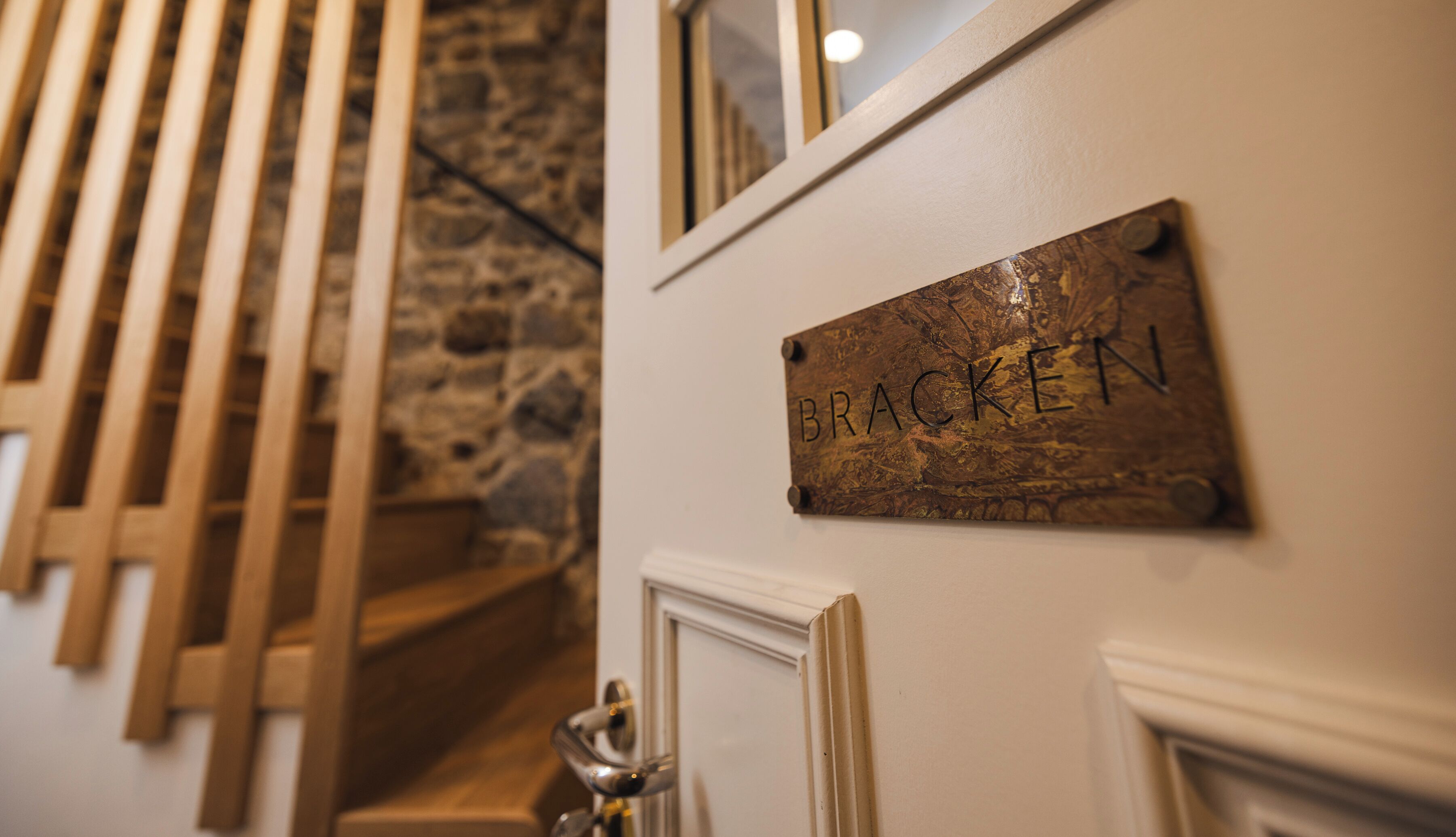 Eine Treppe mit Holzgeländer, einer Steinmauer und einer Tür mit dem Schild 'BRACKEN'.