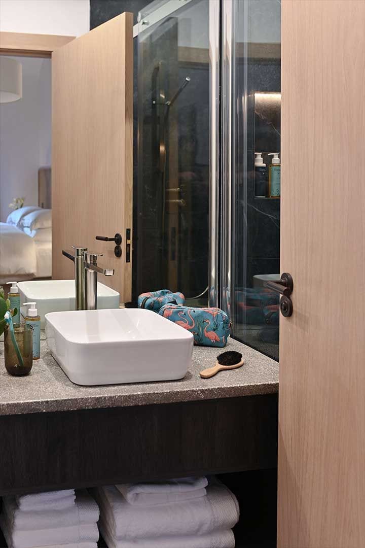 A modern bathroom with a large mirror, two sinks, and a shower.