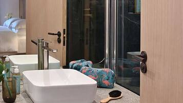 A modern bathroom with a large mirror, two sinks, and a shower.