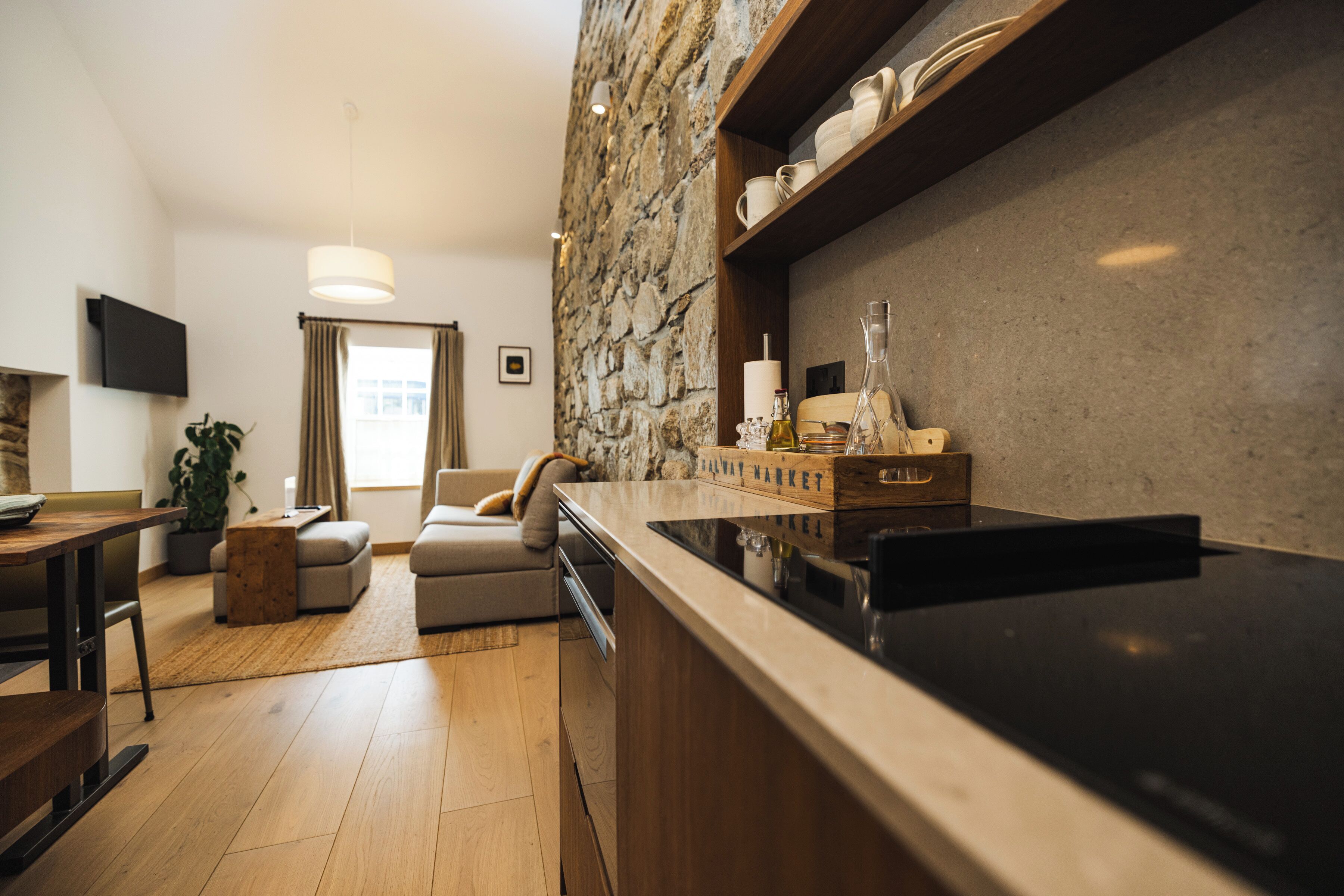 Una cocina moderna con pared de acento de piedra, armarios de madera y encimera negra.
