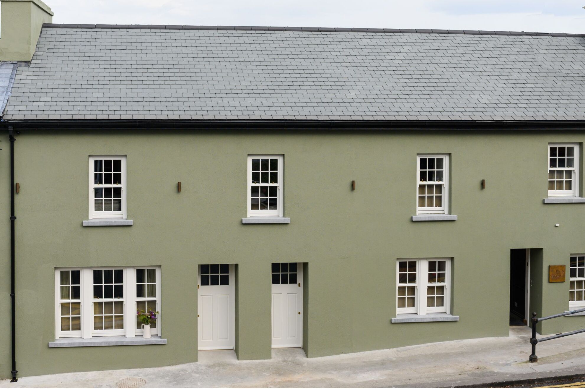 Ein zweistöckiges Gebäude mit flachem Dach und grüner Fassade.