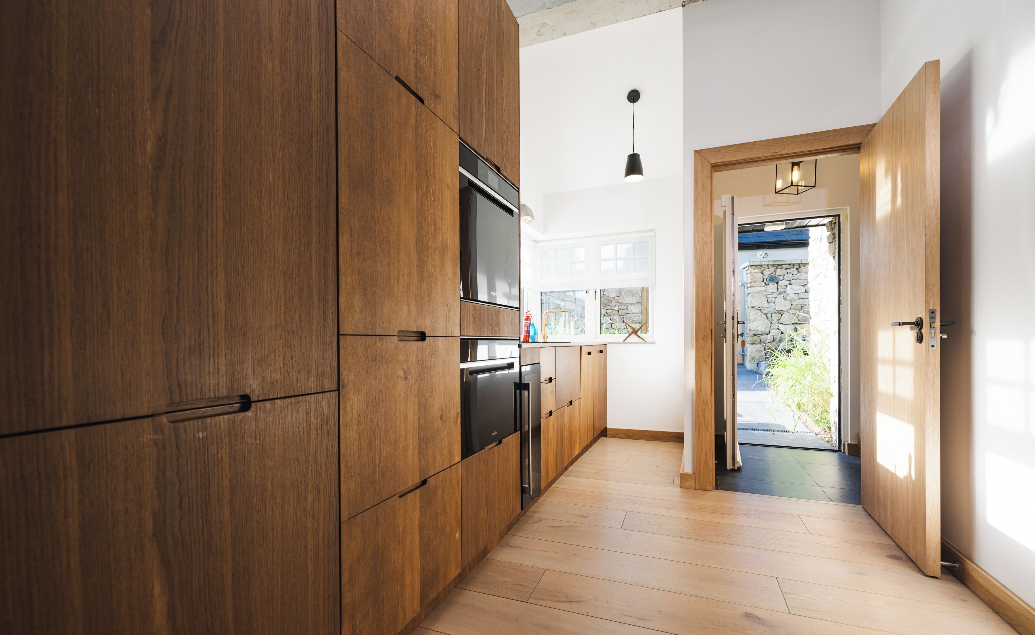 Eine moderne Küche mit Holzschränken, einem eingebauten Backofen und einem Edelstahl-Kühlschrank.