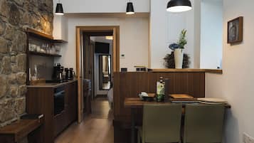 Una cocina moderna con armarios de madera, una zona de comedor con mesa y sillas, y una pared de piedra.
