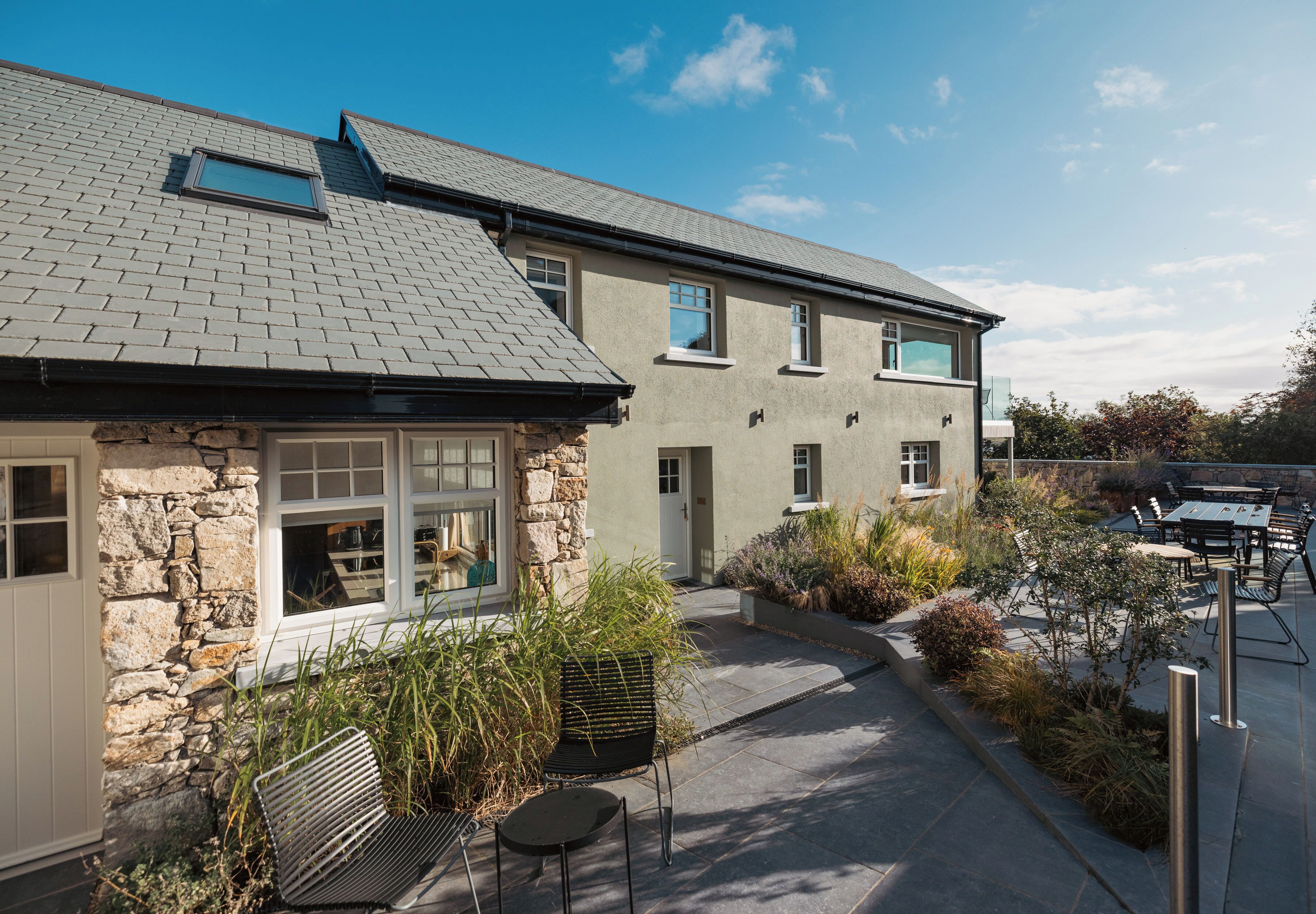 A two-story building with a stone facade, a sloped roof, and a patio area with outdoor seating.