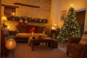 A cozy living room with a fireplace, a Christmas tree, and festive decorations.