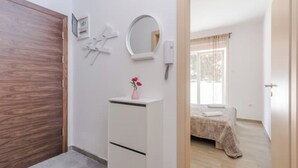 Ein Schlafzimmer mit Bett, Nachttisch, Spiegel und Fenster.