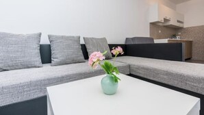 Ein modernes Wohnzimmer mit einem grauen Sofa, einem weißen Couchtisch und einer Vase mit Blumen.