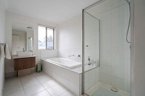 A modern bathroom with a glass-enclosed shower, a large bathtub, and a vanity with a mirror. - Spacious 4B House in PointCook (Point Cook)