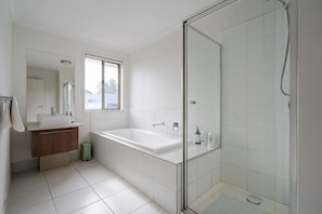A modern bathroom with a glass-enclosed shower, a freestanding bathtub, and a vanity with a mirror. - Spacious 4B House in PointCook (Point Cook)