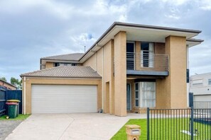 A two-story house with a garage, a balcony, and a well-maintained lawn. - Spacious 4B House in PointCook (Point Cook)