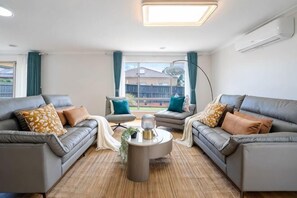 A living room with two sofas, a coffee table, and a lamp. - Spacious 4B House in PointCook (Point Cook)