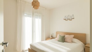 Un dormitorio con cama, mesitas de noche, una lámpara colgante y una lámpara de pared.