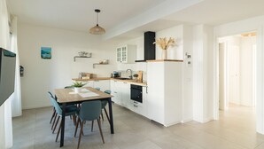 Una cocina moderna con armarios blancos, encimera de madera y comedor con mesa y sillas.