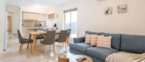 Una sala de estar moderna con un sofá gris, una mesa de centro y un comedor con sillas y una mesa.