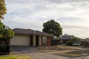 A residential street with houses, a driveway, and a large tree. - Modern 3B2B1C Home in Doreen (Mernda)