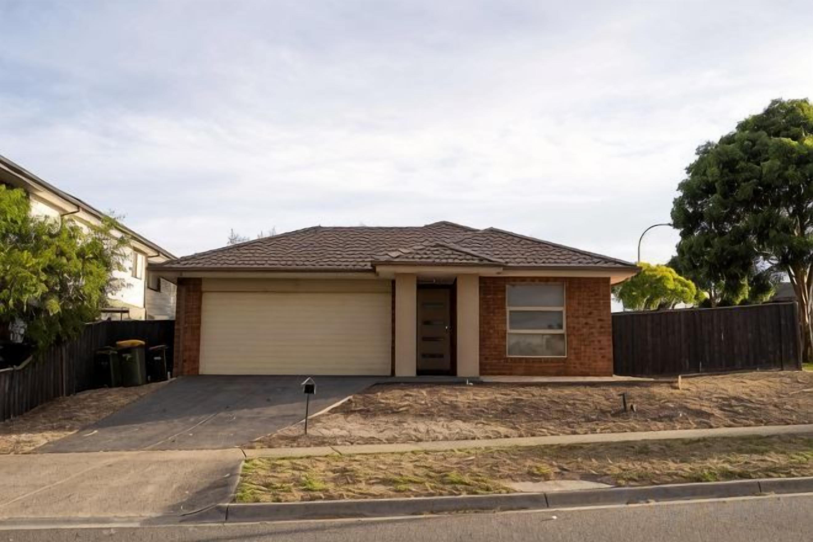 A single-story house with a garage, a front yard, and a tree.