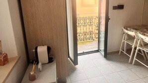 Una habitación pequeña y bien iluminada con un armario de madera, una mesita con una silla y piso de baldosas.