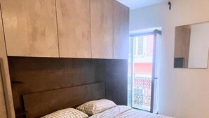Un dormitorio con una cama grande, cabecera y puerta corredera hacia un balcón.