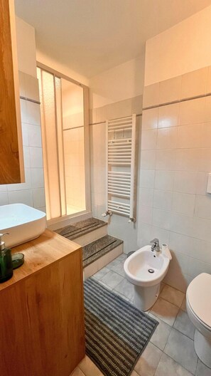Un baño moderno con lavamanos, bidé y zona de ducha blanca.