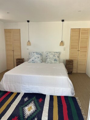 Ein Schlafzimmer mit einem großen Bett, zwei Nachttischen, Holzschränken und einem farbenfrohen Teppich.