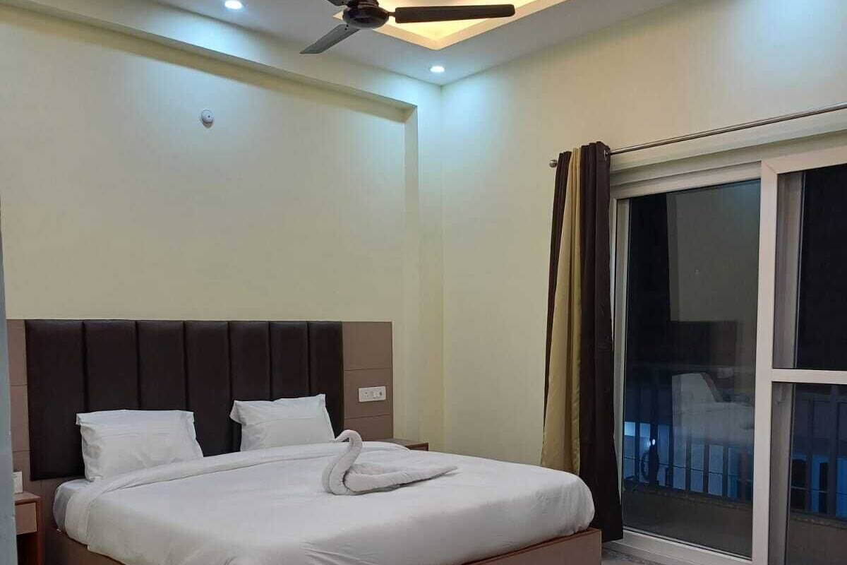 A modern bedroom with a large bed, a ceiling fan, and a view of the outside through a large window.