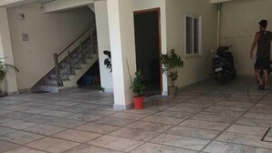 A spacious indoor area with tiled flooring, a staircase, and potted plants. - Sampati Homestay (Rishikesh)