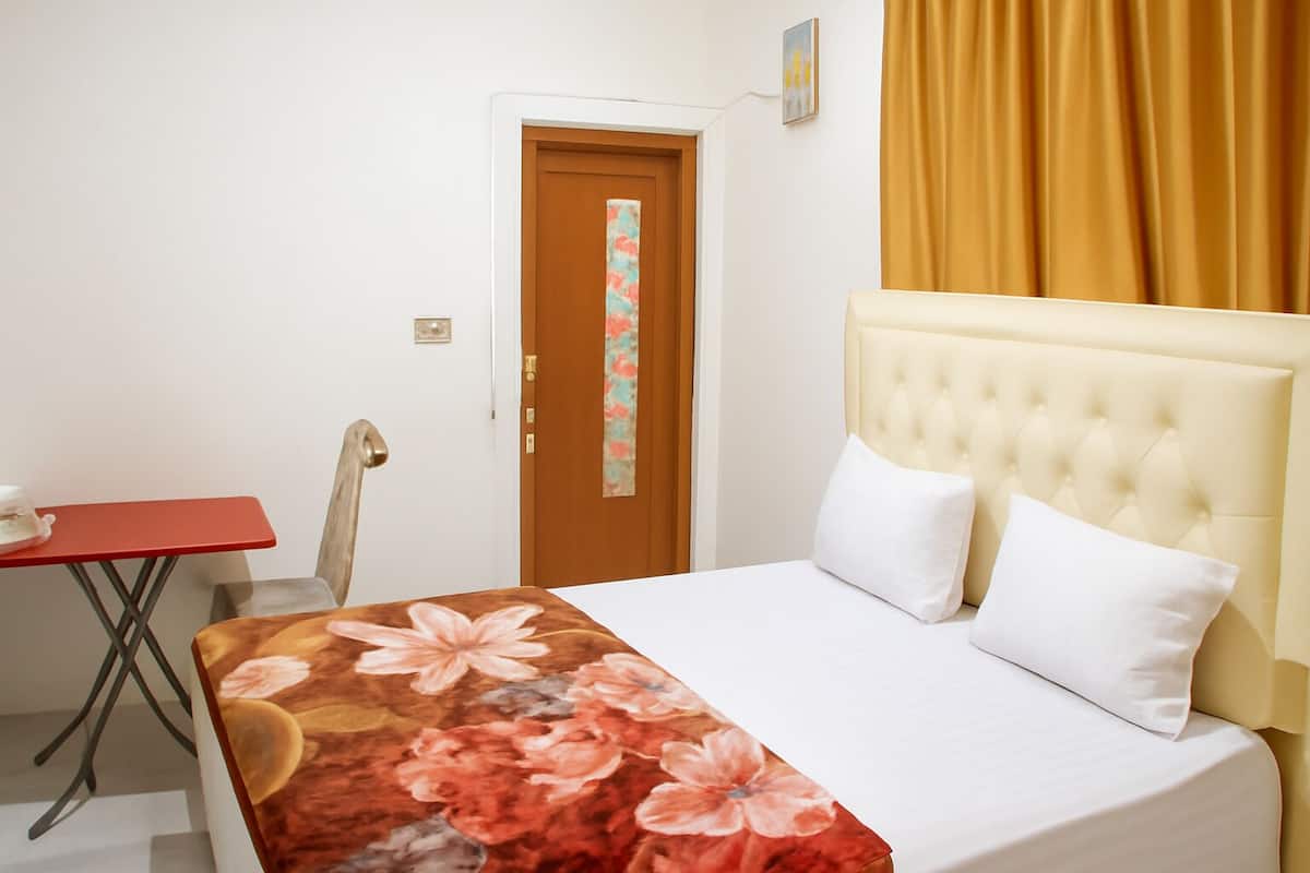 Ein Hotelzimmer mit einem Bett, einem roten Tisch, einem Stuhl und einer Tür.
